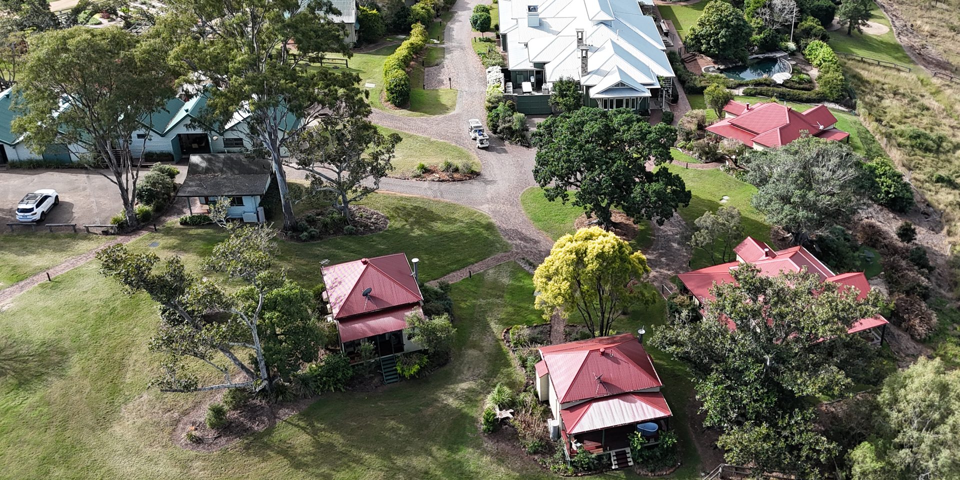 Aerial view of maintained lawns, gardens and grounds across a resort property in South East Queensland