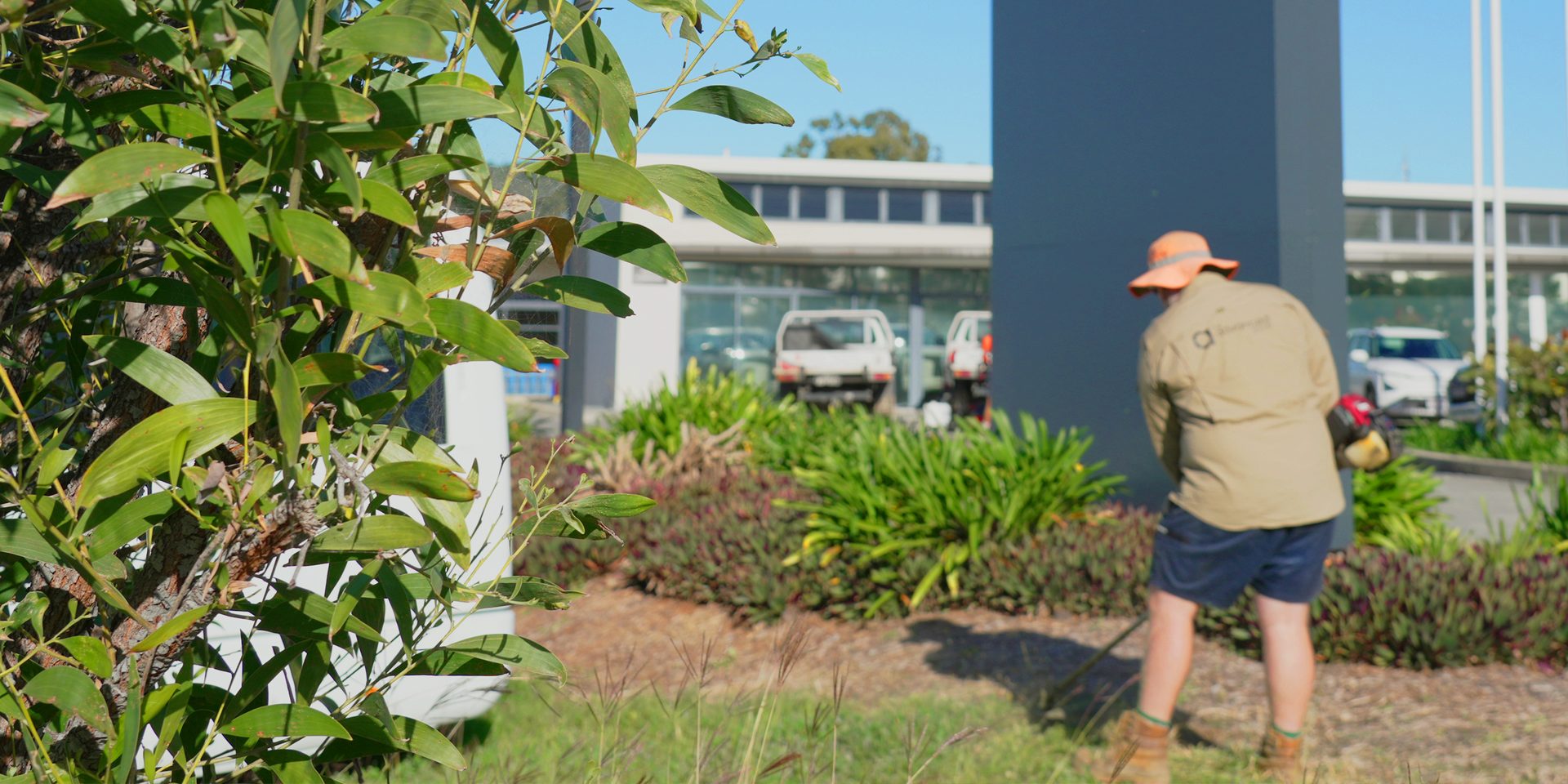 Advanced Landscaping crew member maintaining garden beds at a commercial premises